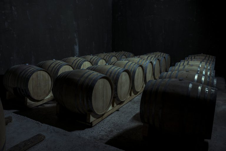 Botellas de vino en estanterías de madera iluminadas en una bodega